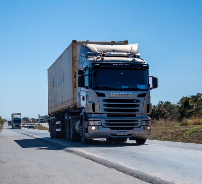 A large cargo truck travels on a highway in Brazil under clear blue skies.